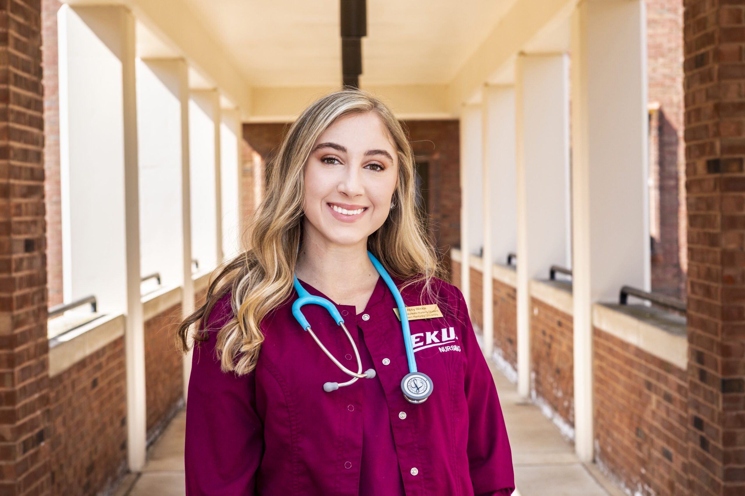 Nursing student wearing maroon scrubs and stethoscope