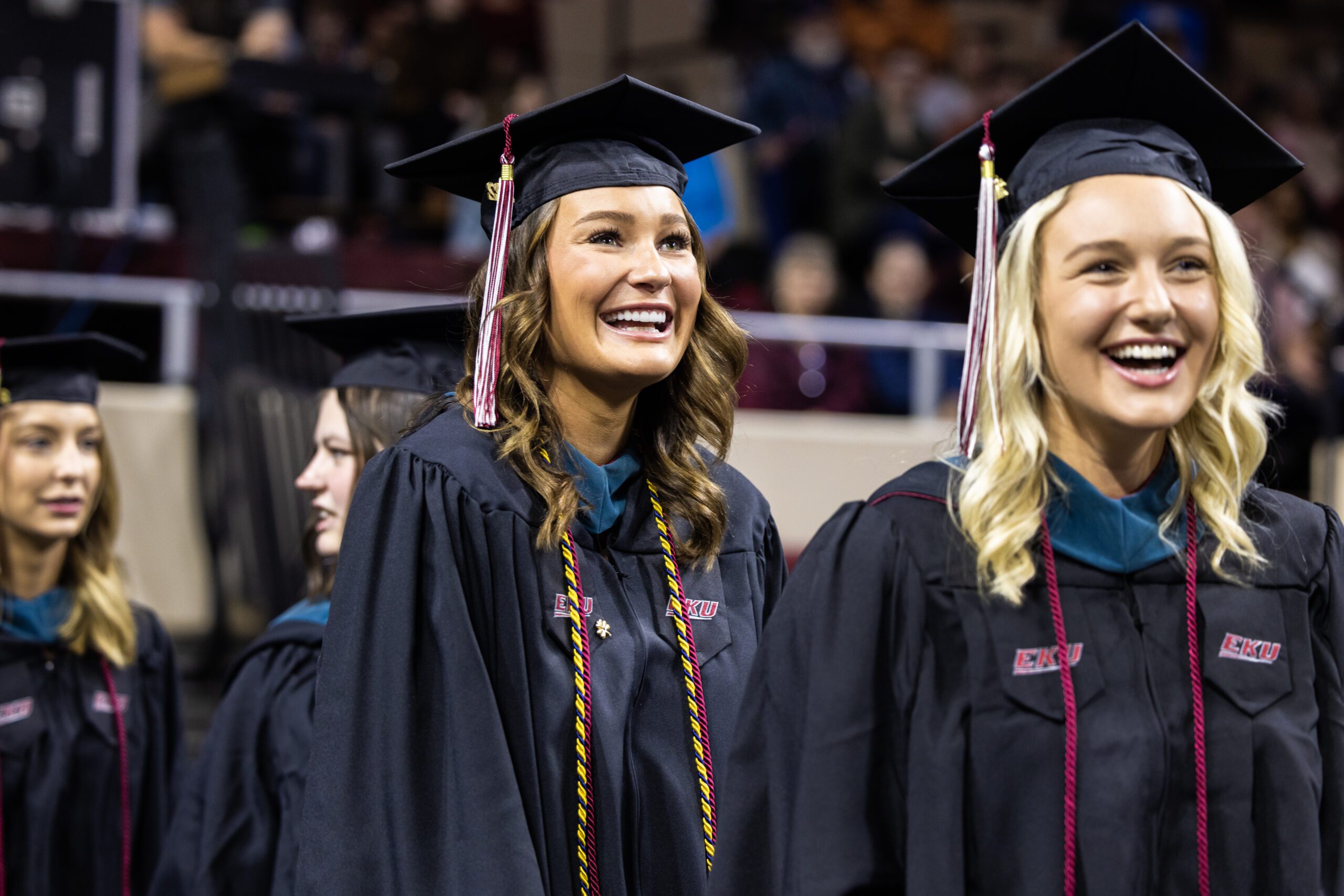 Graduating nursing students wearing cap and gown smile at commencement ceremony