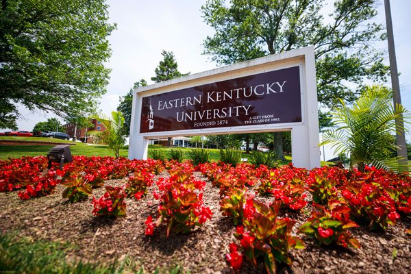 an Eastern Kentucky University entrance sign with red flowers