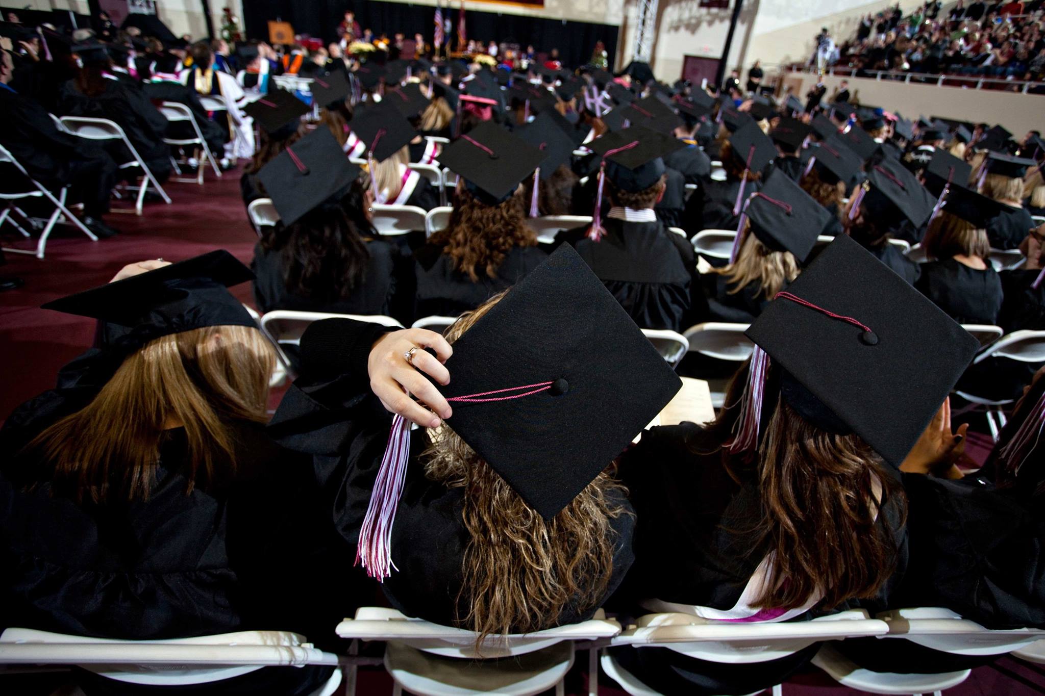 View of students wearing graduation cap and gown from behind
