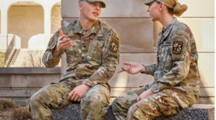 Two people in military uniforms talking.