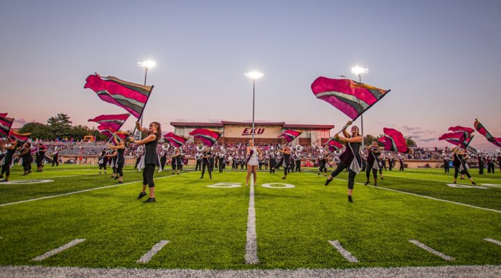 students in the color guard perform on the football field