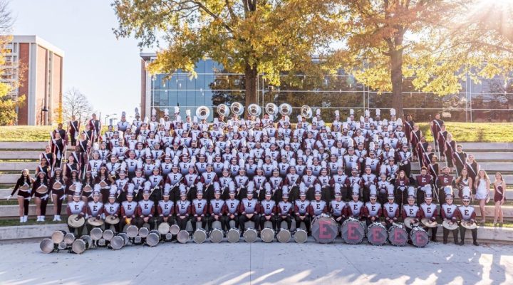 the Marching Colonels pose outside in full uniforms with instruments