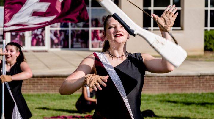 a member of the color guard twirls a rifle