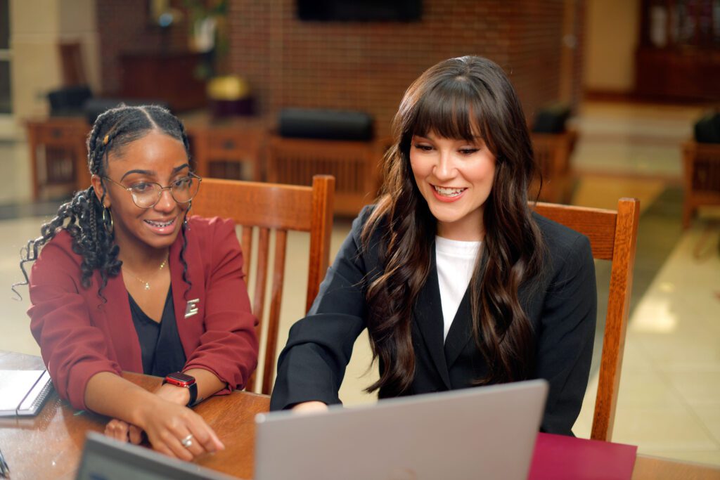 an advisor helps a student on a laptop