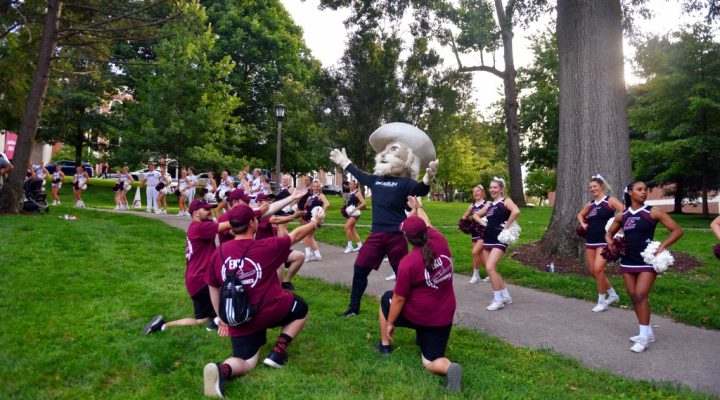 EKU students kneeling, pointing at Colonel mascot at Big E Welcome.