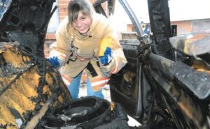 An alumni conducting an investigation of a burned vehicle.