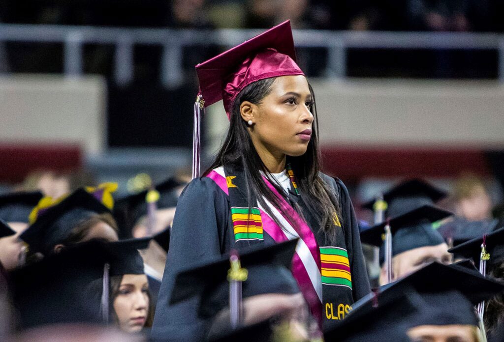 an EKU Honors Scholar standing during commencement with sitting students around her