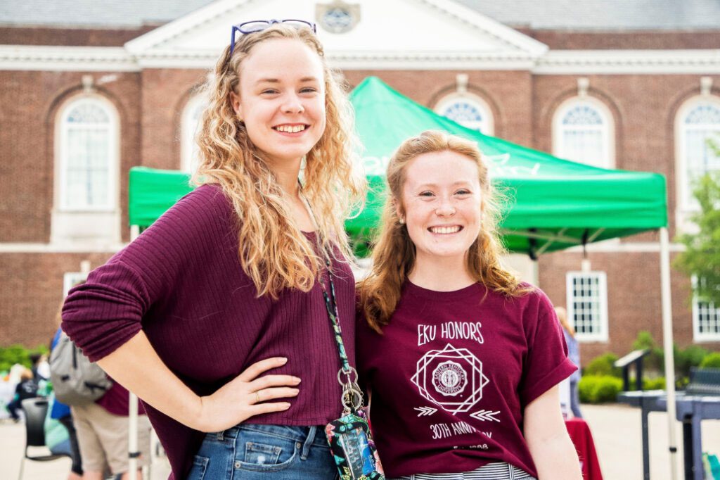 Two EKU Honors students smile at an outdoor event