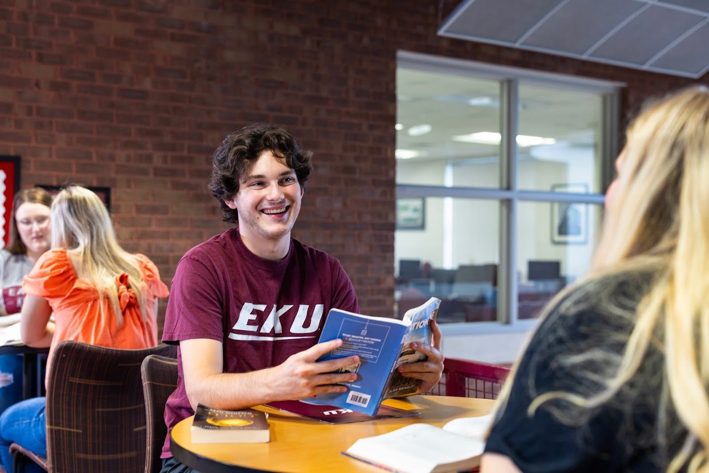 An EKU Manchester student holding a textbook.