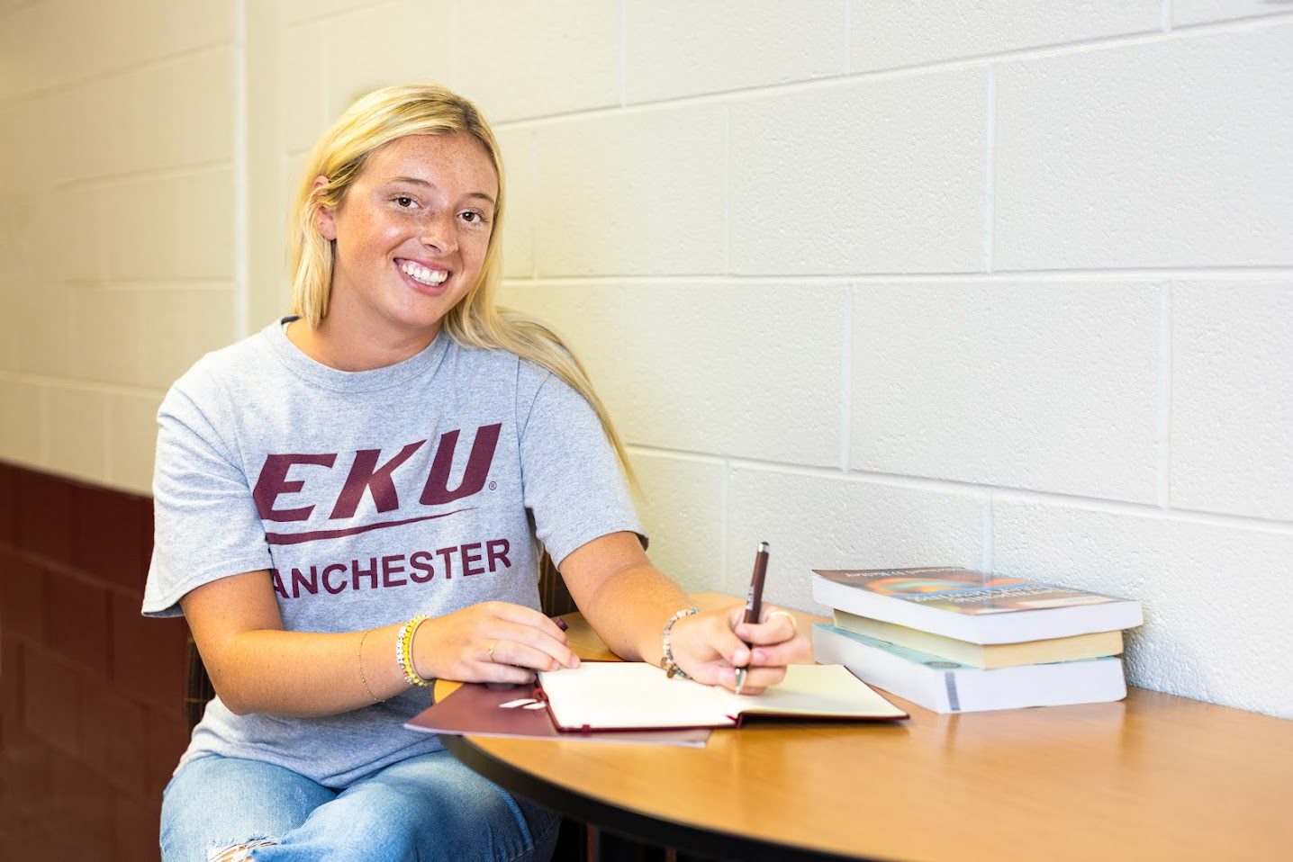 An EKU Manchester student writing in a notebook.