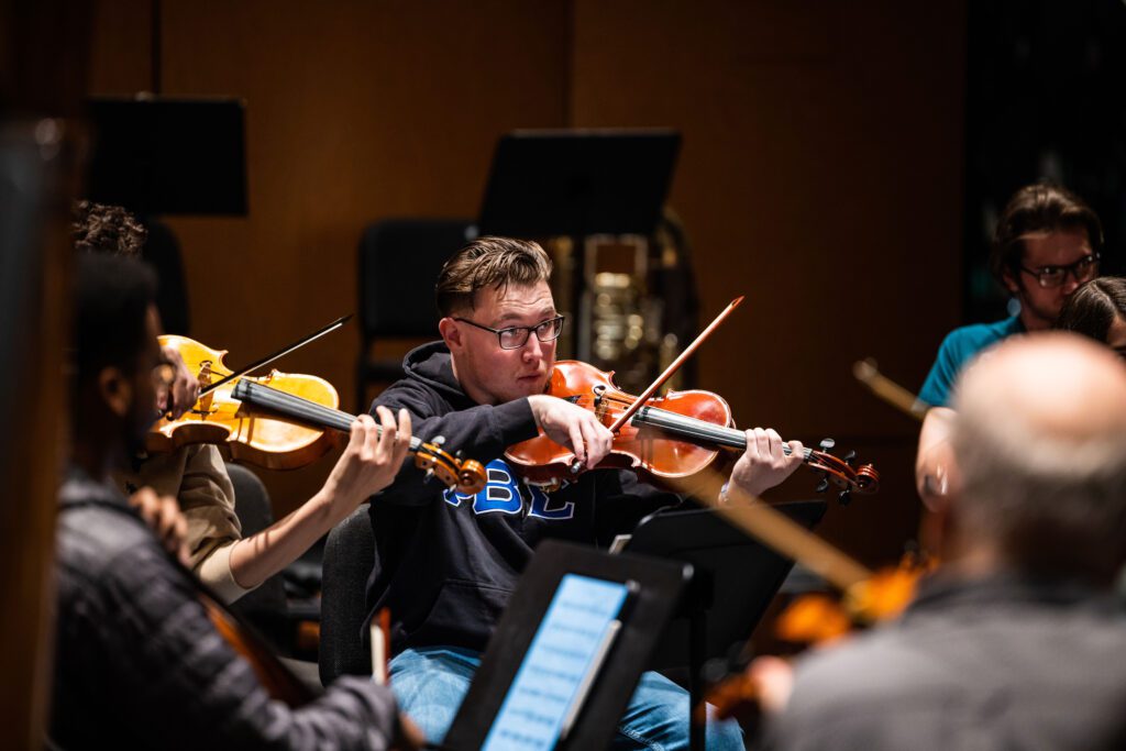 students play violins during an orchestra rehearshal