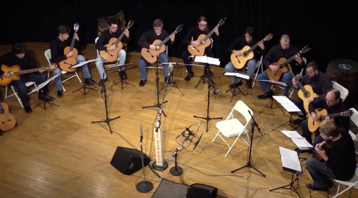 students and faculty playing guitars onstage