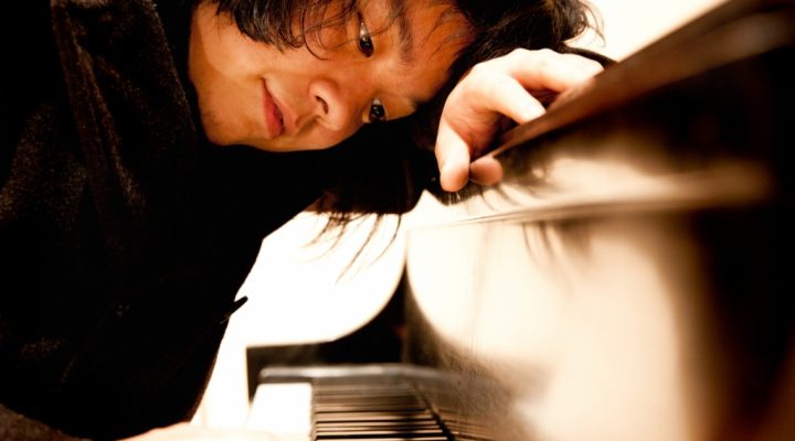 a student leans over a piano keyboard