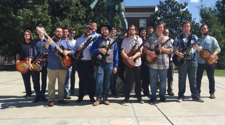 students pose outside with electric guitars