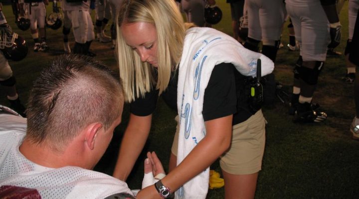 An image of a medic wrapping an Eastern Kentucky University football player's wrist.