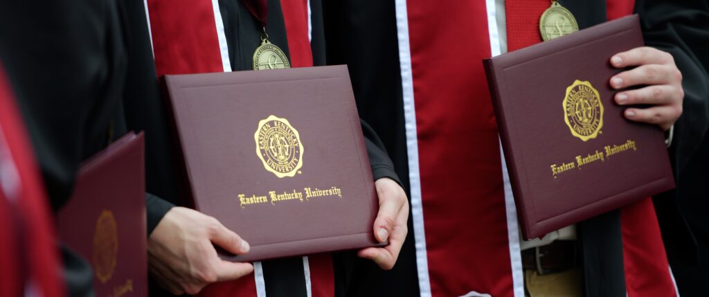 An image of students holding their diplomas after graduating from Eastern Kentucky University.