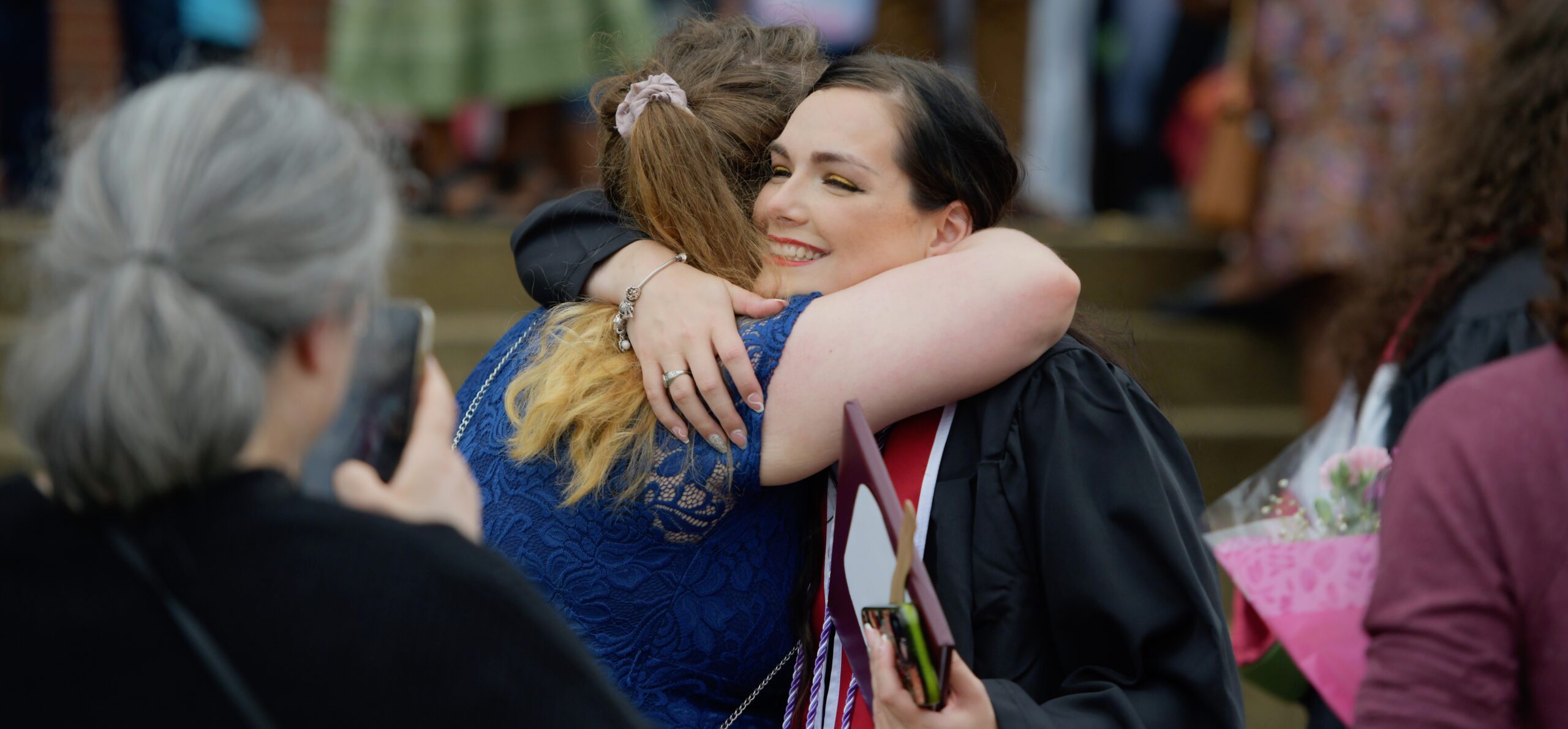 An image of an Eastern Kentucky University gradate hugging a guest.