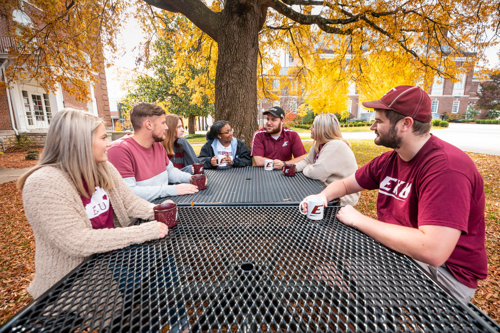 students sitting around an outside table in the fall