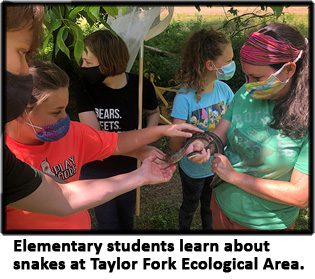Elementary students hold a snake