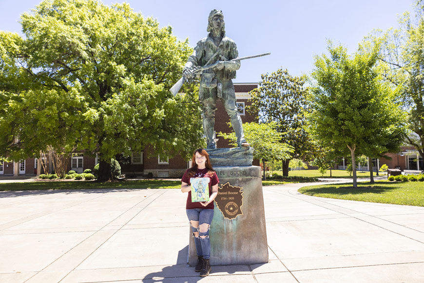 Ashley Fletcher holding finished watercolor in front of Daniel Boone statue