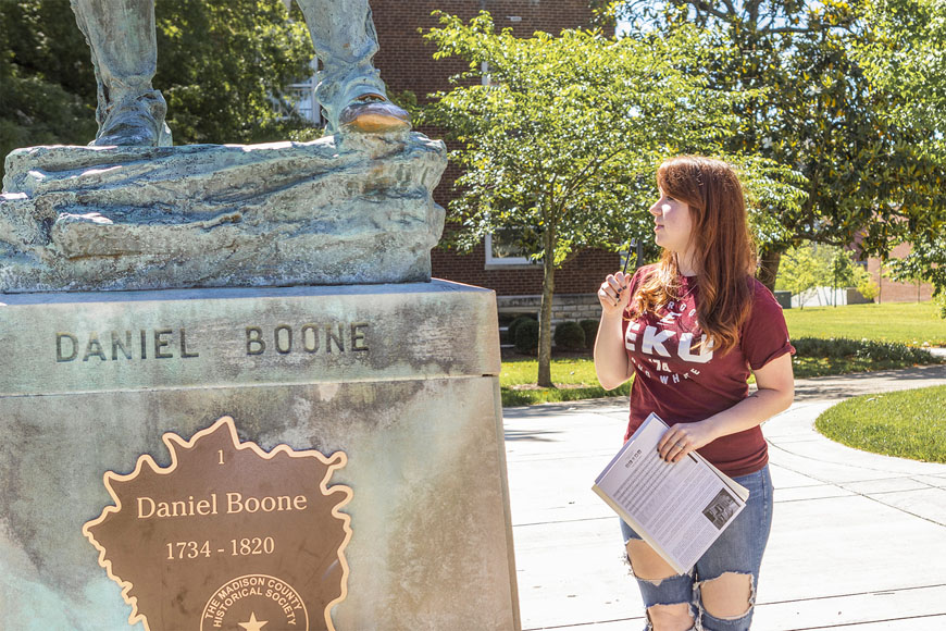 Ashley Fletcher looking at Daniel Boone statue holding a pencil to her face
