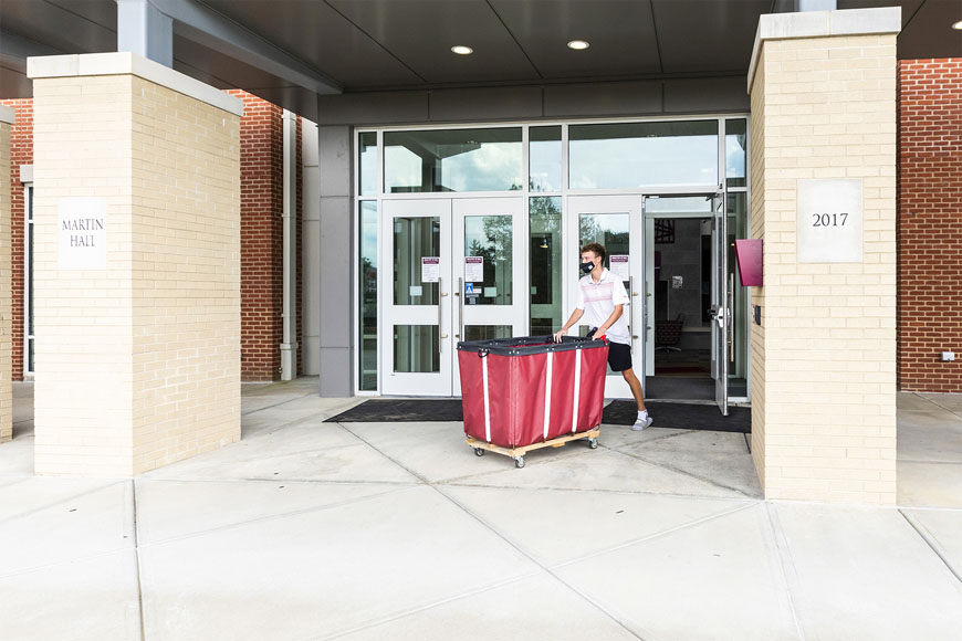 One student pushing cart out the doors of Martin Hall during Move in week