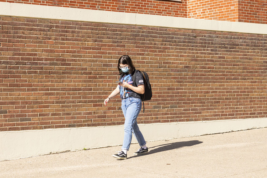 Student walking in front of brick wall during their first day of classes