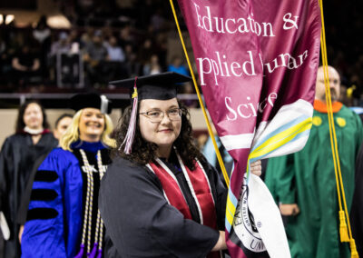 Graduate carrying college banner at ceremony