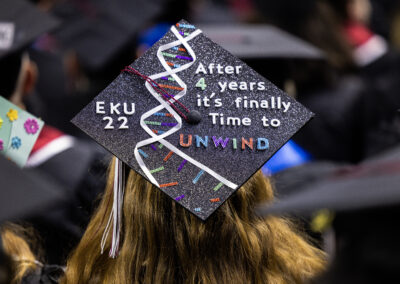 A focused shot on a graduate's cap that reads "EKU 22 After 4 Years it's time to Unwind"
