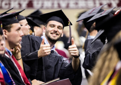 Smiling graduate gives thumbs up to the camera