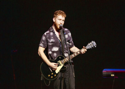 JP Saxe on guitar while singing into microphone