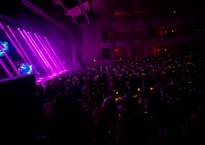 Concert crowd with glow sticks illuminated by pink stage lighting