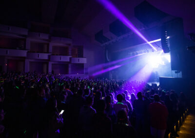 Purple stage lighting beam across the concert crowd