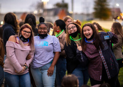 A group of excited students with glowsticks pose together