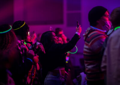 Concert attendee smiles while recording the performance with a smartphone