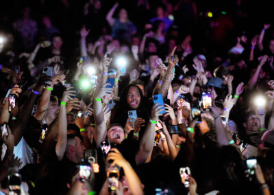 Students holding up lit cellphones with one arm during concert