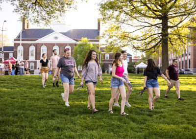 students walking across lawn in front of brick building