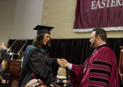 A graduate at Eastern Kentucky University's Fall 2023 Commencement ceremony shaking hands with the president.