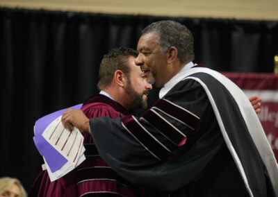 A graduate at Eastern Kentucky University's Fall 2023 Commencement ceremony on stage with the president.
