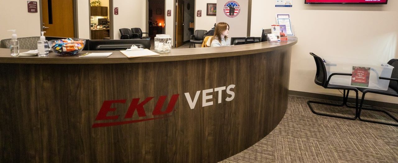 a woman sits behind the desk of the EKU Veterans Affairs Office