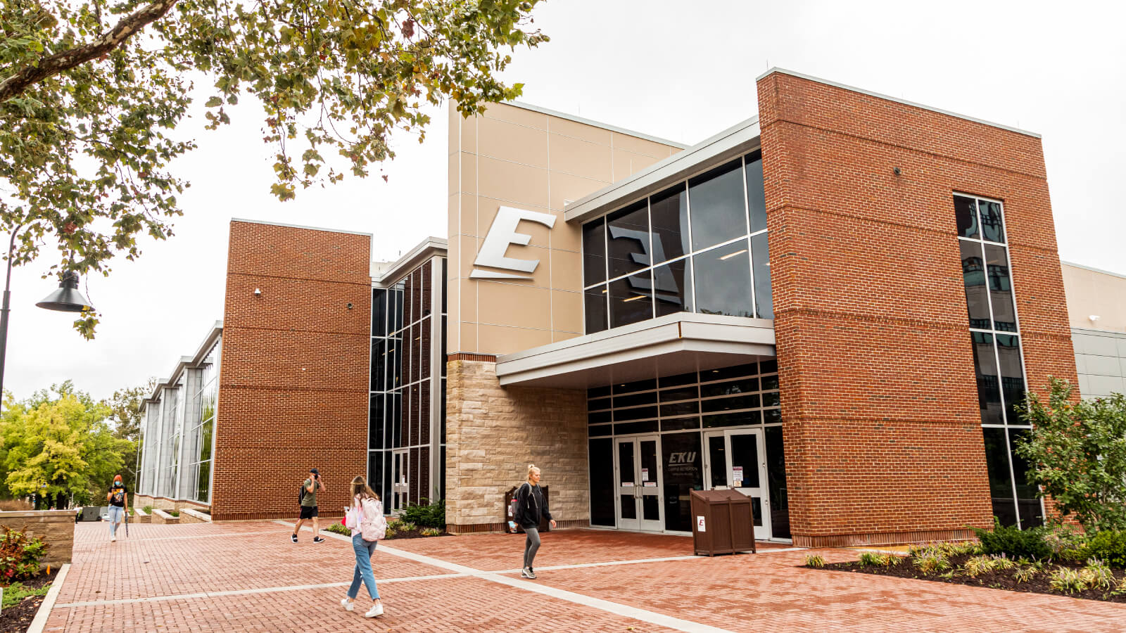 Student rec center on a sunny day with students walking in front of it