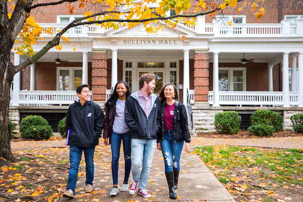 Four students walk on campus in fall