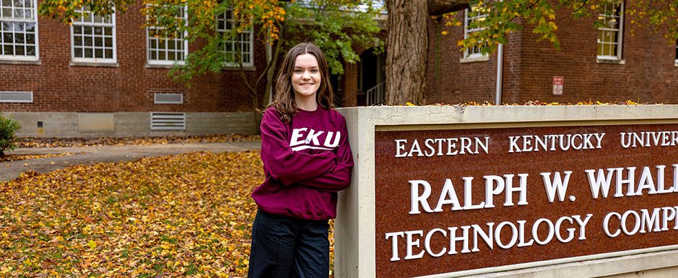 a student poses beside EKU's Whalin Technology Complex sign