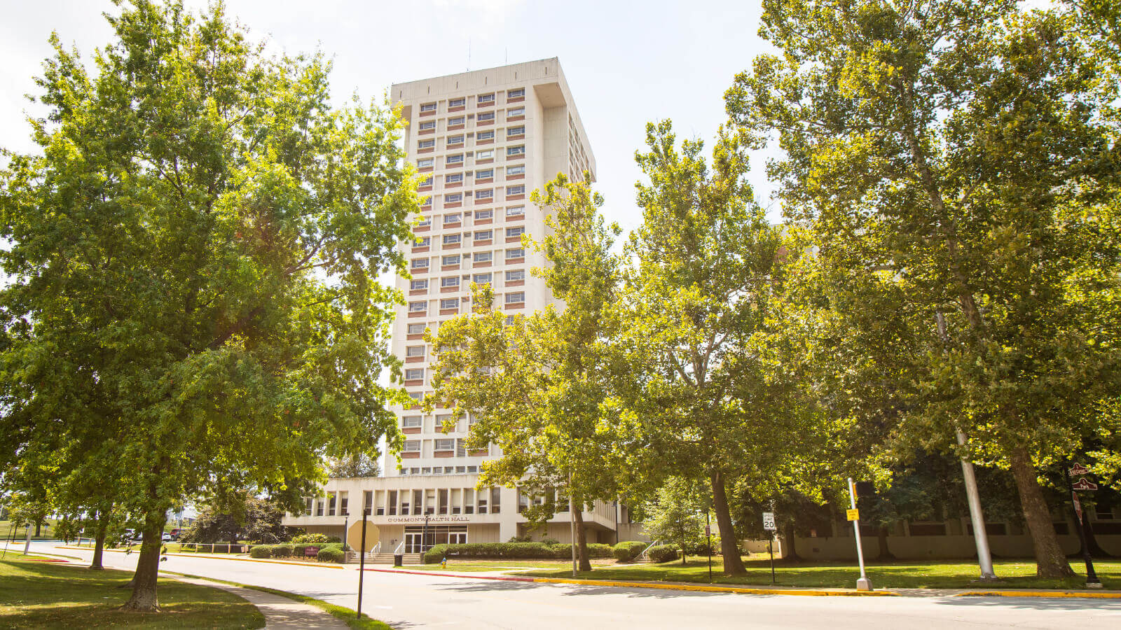 Front view of Commonwealth Hall framed by green trees.