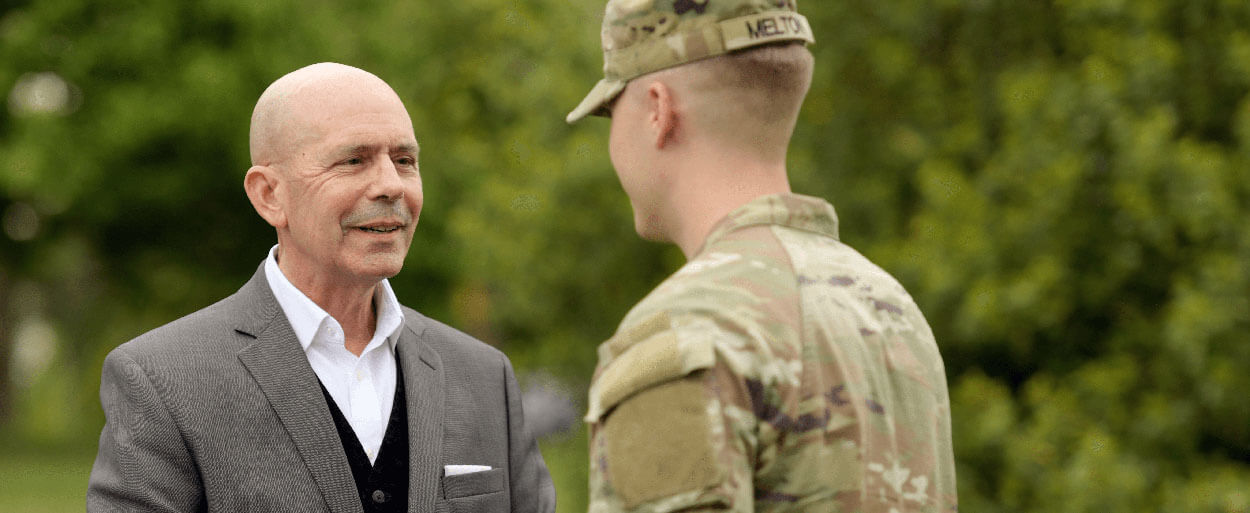 Header image of Brian Brode shaking hands with young military member Melton