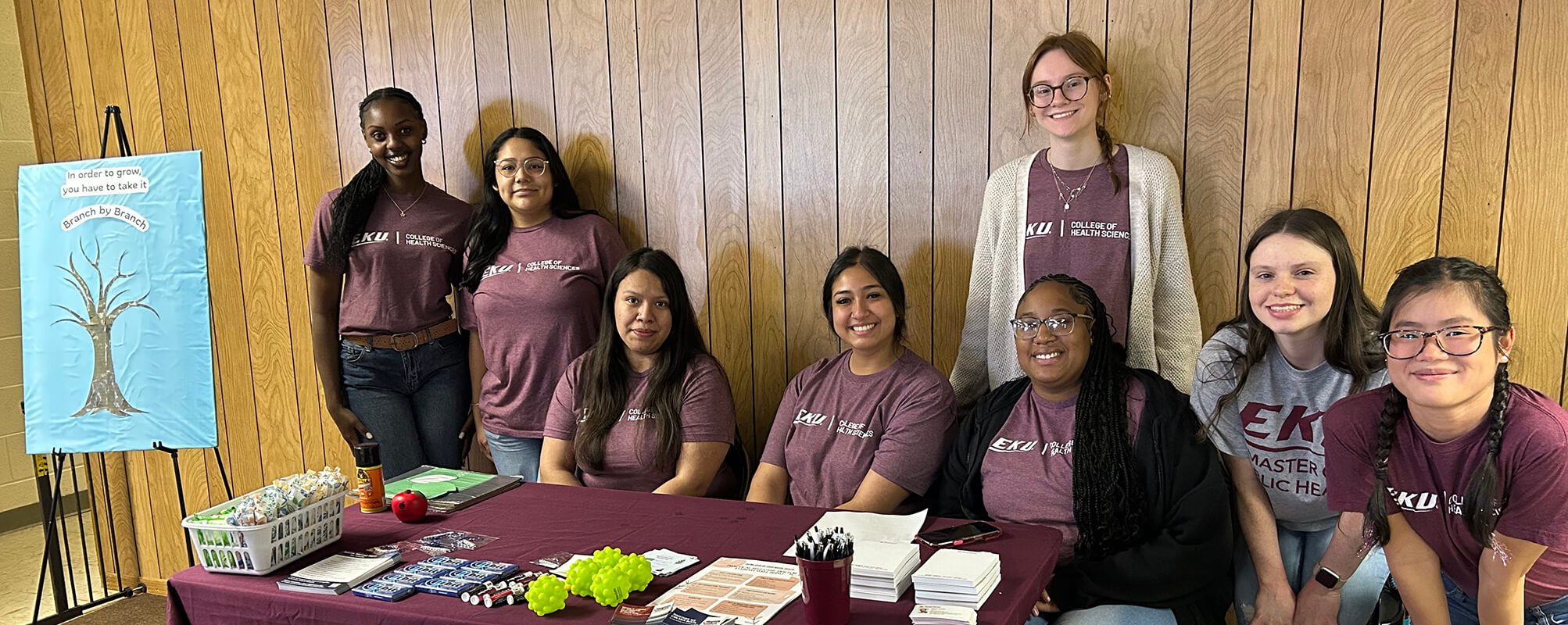 large group of eku public health students gathered around a table at the enrich needs fair
