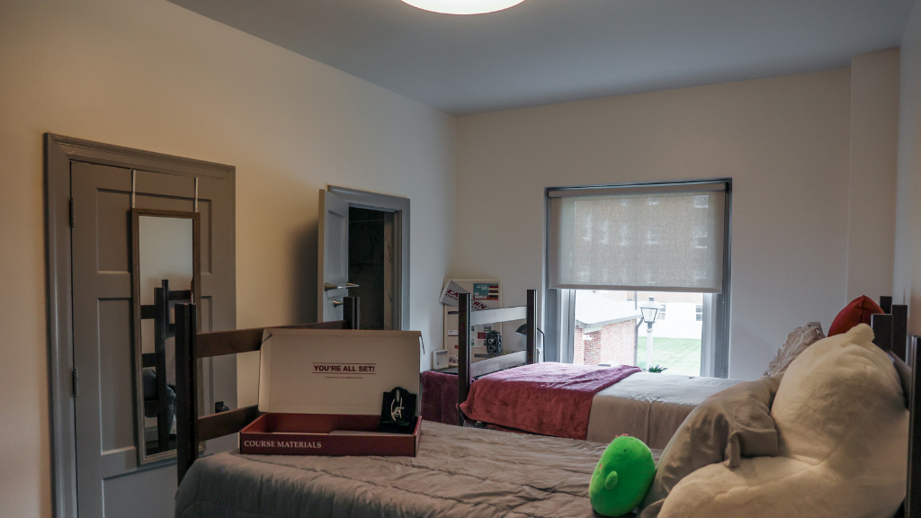 two beds in a shared suite room with a door open leading into the suite's bathroom