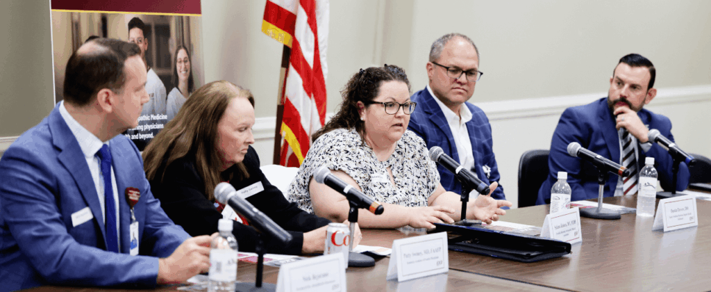 group of well-dressed people sit at conference table with microphones