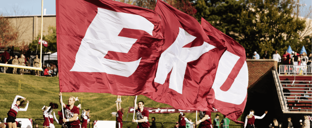 waving EKU flag in foreground with eku cheerleaders in background